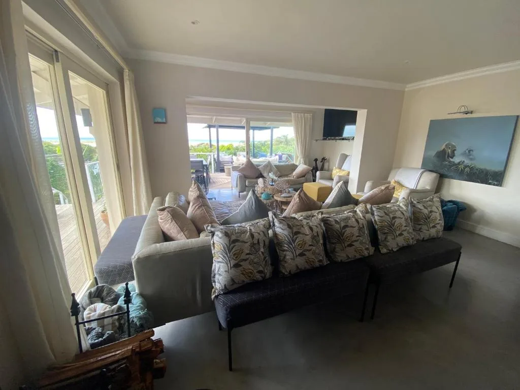 Spacious lounge with sofa, comfortable seating, and ocean views through glass doors