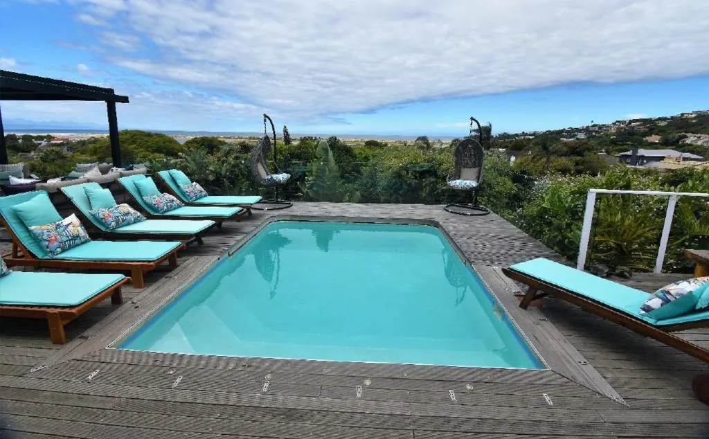 Swimming pool with turquoise loungers overlooking coastal landscape and ocean