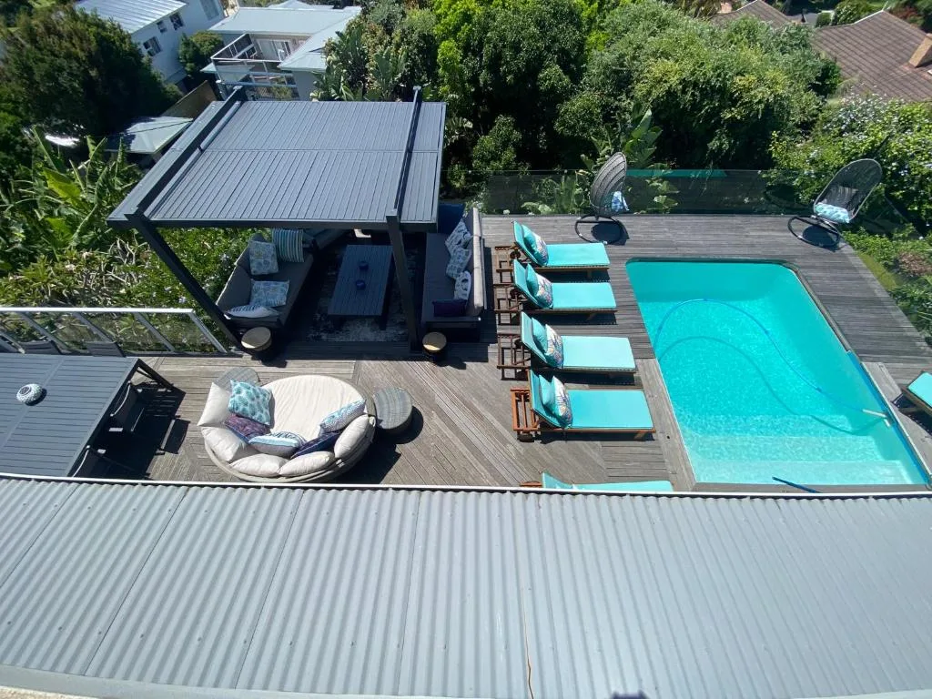Turquoise swimming pool with loungers on wooden deck and shaded seating area