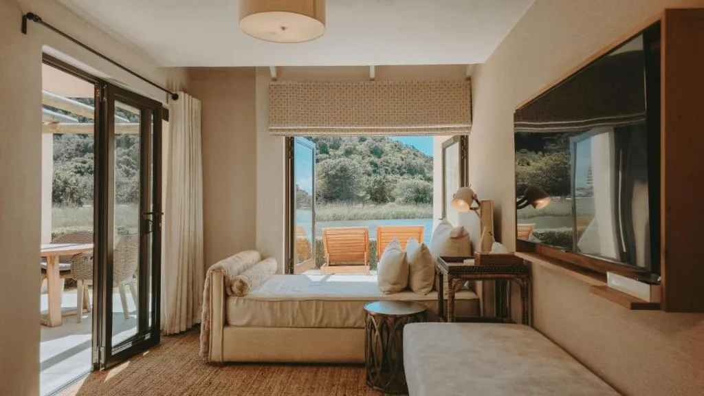 Bright bedroom with bed overlooking lagoon and wooden deck area