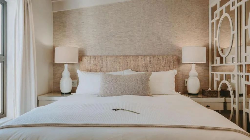 Modern bedroom with neutral bedding, woven headboard, and white bedside lamps
