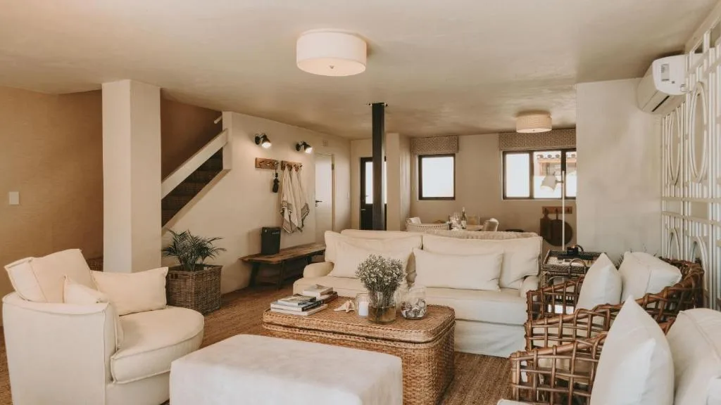 Spacious open-plan lounge with cream sofas, woven coffee table, and fireplace
