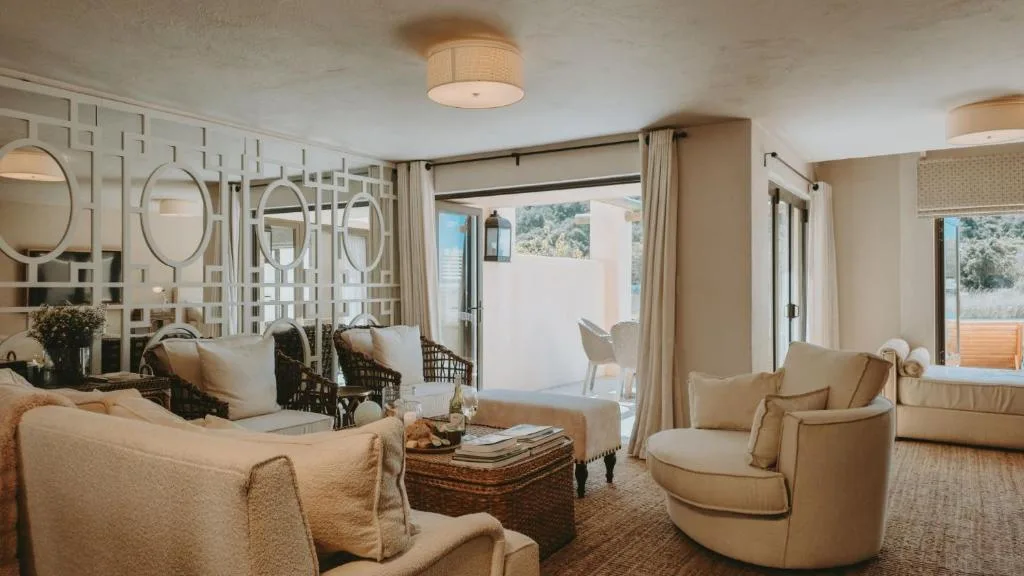 Spacious lounge with cream sofas, decorative mirrors, and garden views