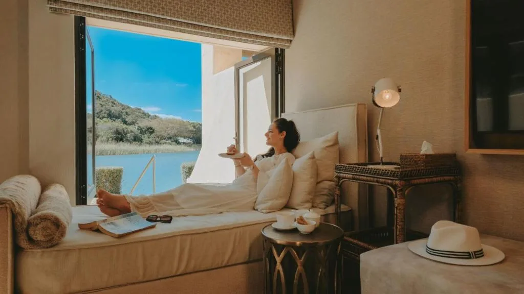 Woman relaxing on window seat overlooking scenic lagoon and mountains