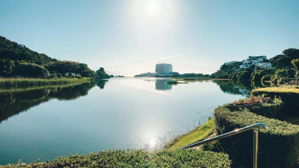 Serene lagoon view with lush vegetation and distant hotel building