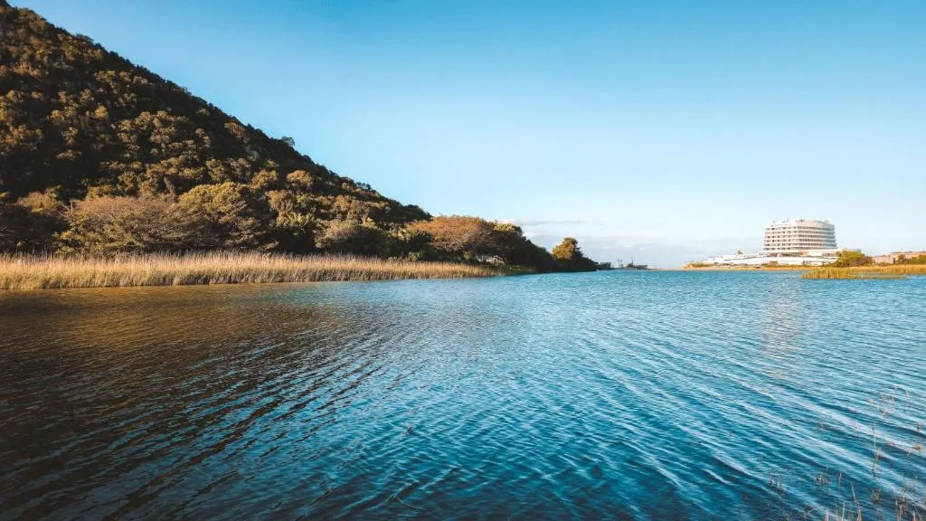 Turquoise lagoon waters with forested hillside and coastal development beyond