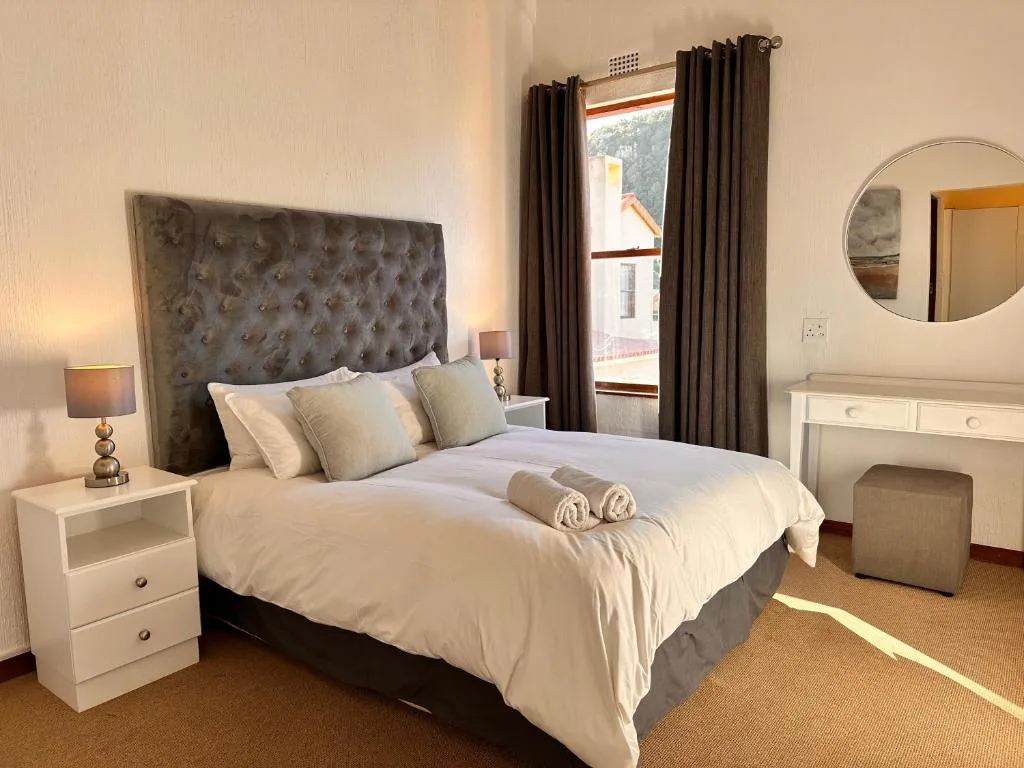 Spacious bedroom with upholstered grey headboard and white bedding