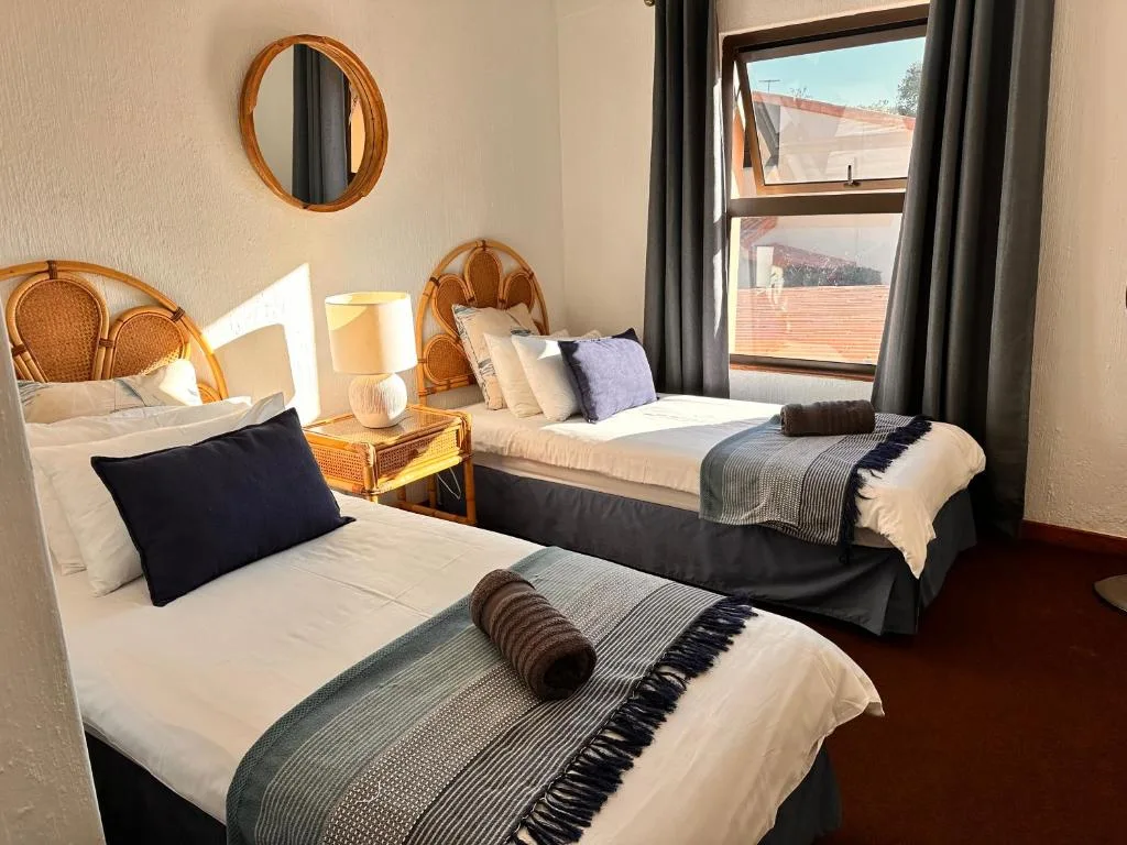 Bright twin bedroom with wooden headboards and mountain views through windows