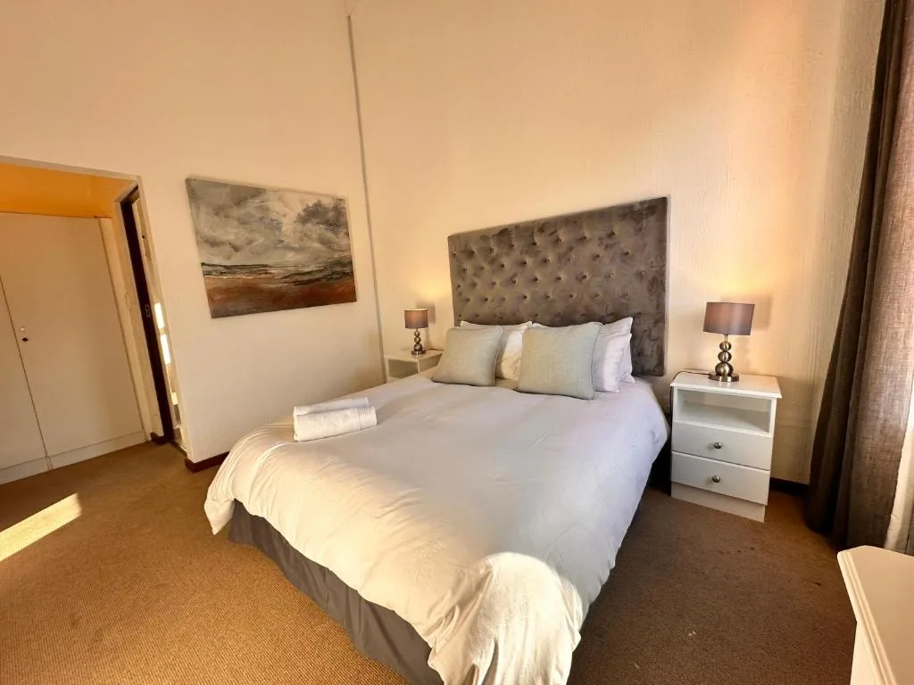 Bright bedroom with queen bed, gray upholstered headboard, bedside tables