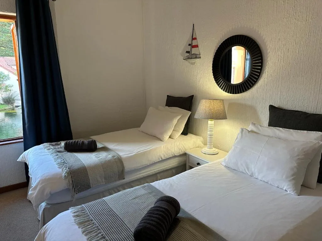 Twin beds with white linens and decorative mirror in bright room