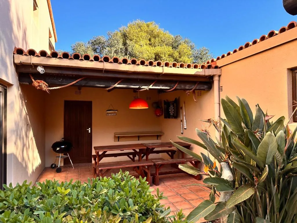Covered patio with wooden dining table, braai grill, and succulent plants