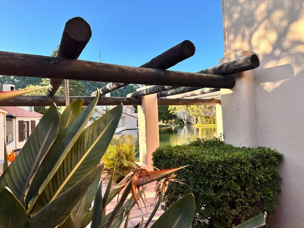Wooden pergola with river views, tropical plants, and surrounding gardens