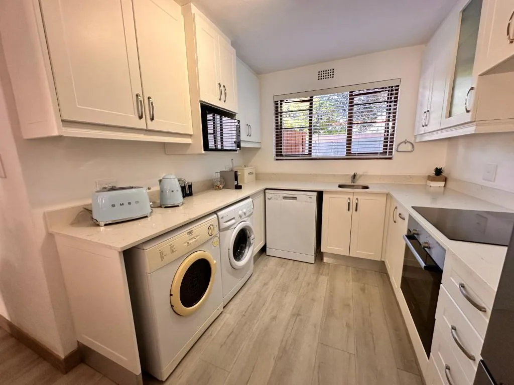 Modern kitchen with white cabinetry, washing machine, dishwasher, and stove