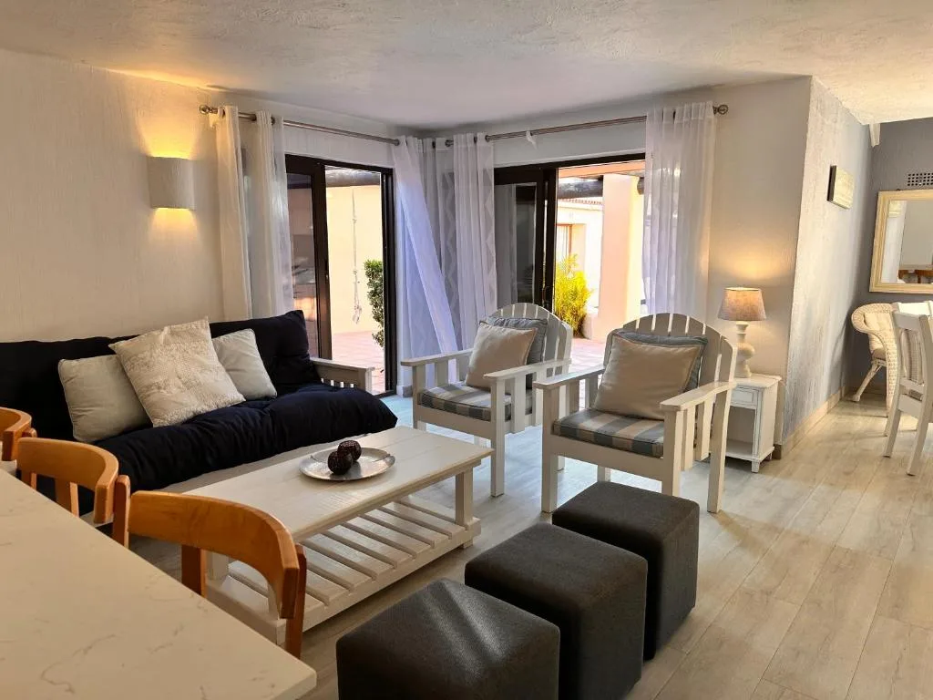 Modern lounge with black sofa, wooden chairs, and deck access doors