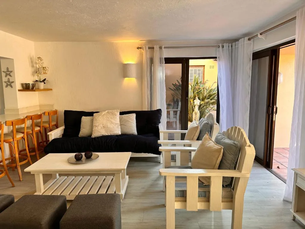 Modern living room with black sofa, wooden furniture, and garden view doors