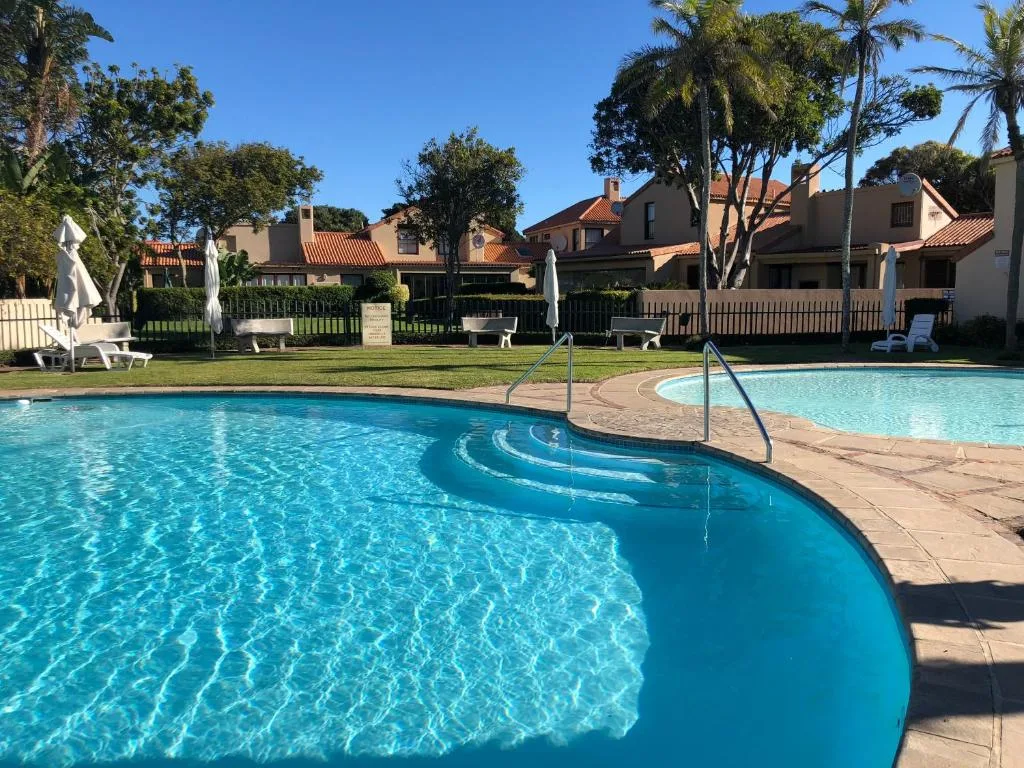 Sparkling curved swimming pool with residential buildings and manicured gardens beyond