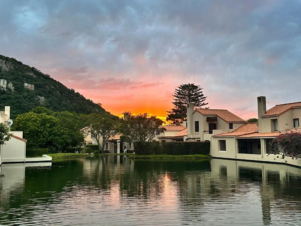Waterfront properties with dramatic sunset sky and forested hillside backdrop