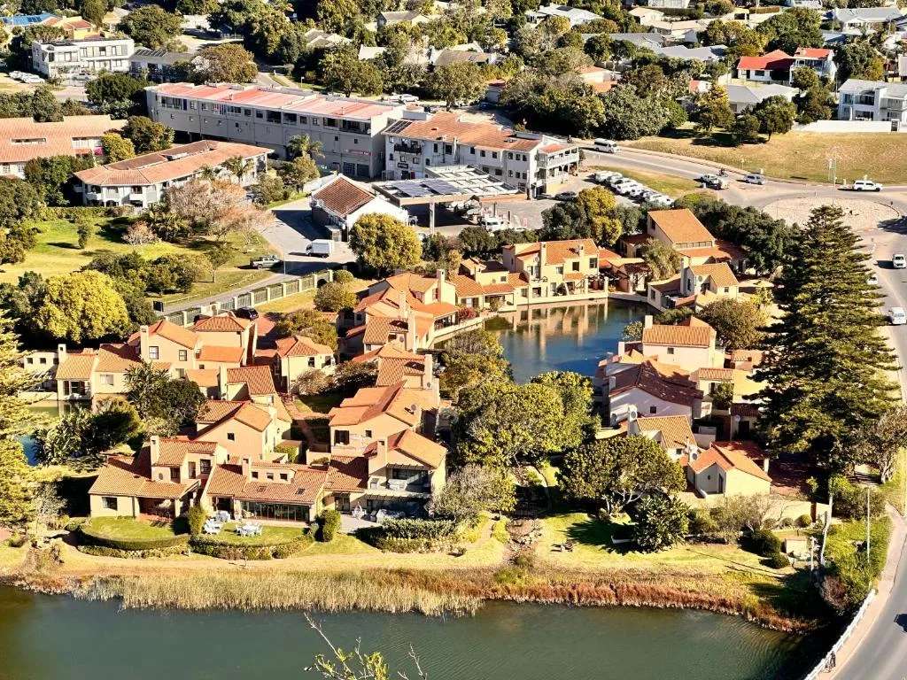 Aerial view of riverside accommodation complex with lagoon waterfront and surrounding gardens