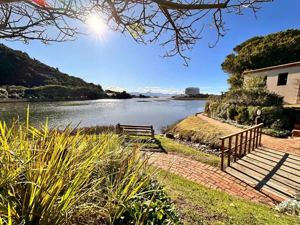 Scenic lagoon view with surrounding hills, lush gardens, and waterfront access