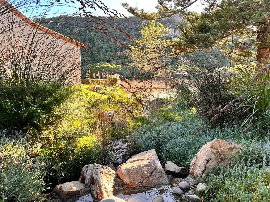 Lush garden with mountain backdrop and water visible in distance