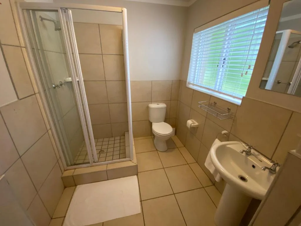 Spacious bathroom with shower enclosure, toilet, and pedestal sink