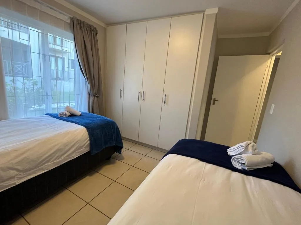 Spacious bedroom with two single beds, built-in wardrobes, and large windows