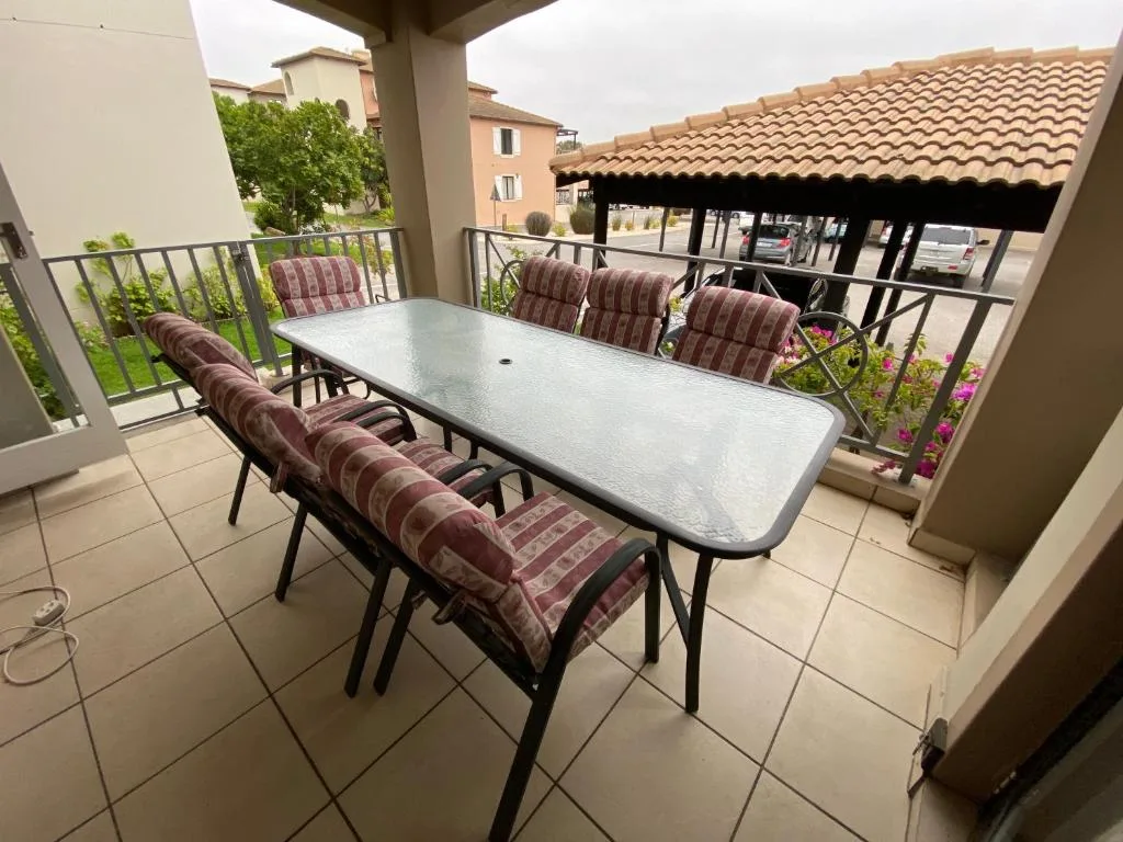 Covered outdoor patio with dining table and cushioned chairs overlooking neighborhood