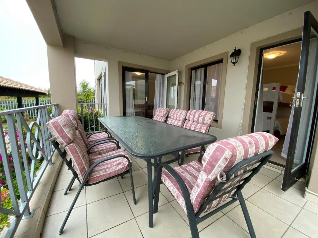 Covered patio with dining table and striped cushioned chairs overlooking garden