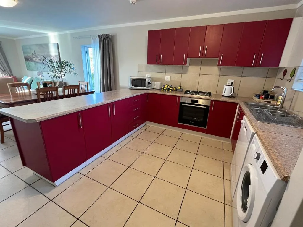 Modern kitchen with burgundy cabinetry, stainless steel appliances, and marble countertops