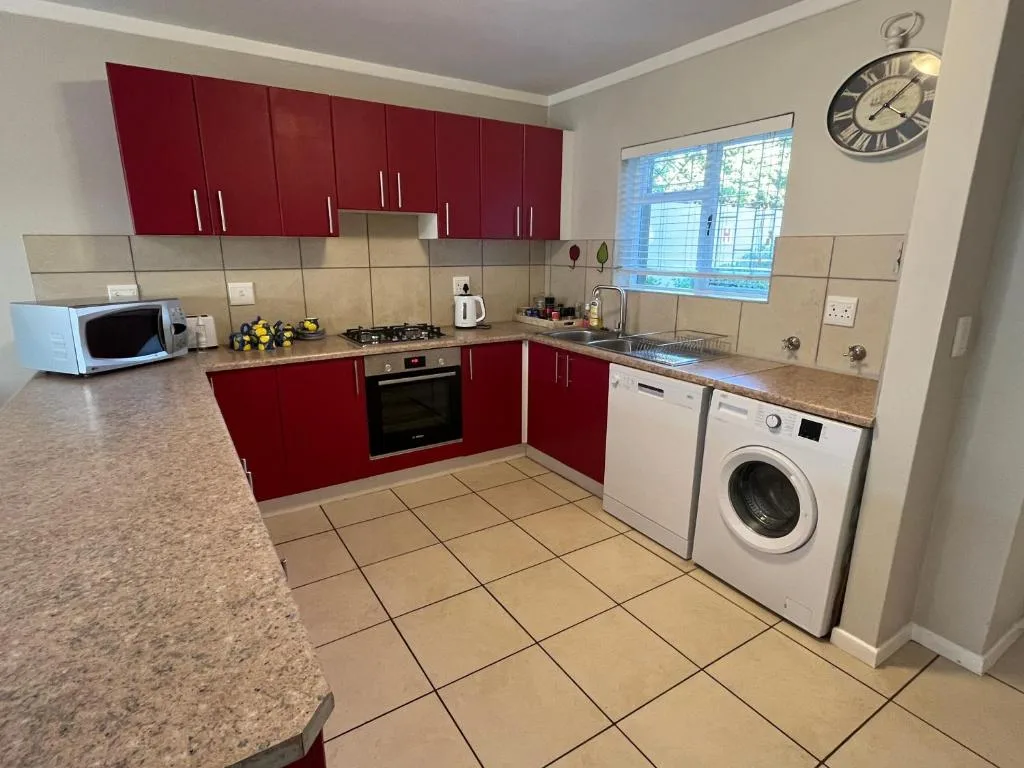 Modern kitchen with red cabinetry, stainless steel appliances, and granite countertops