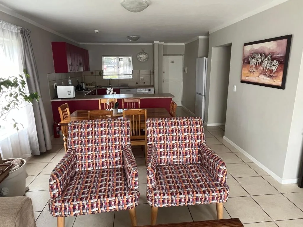 Open-plan living area with patterned armchairs and kitchen visible in background