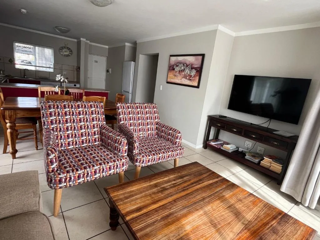 Open-plan lounge with patterned armchairs, TV, and wooden coffee table