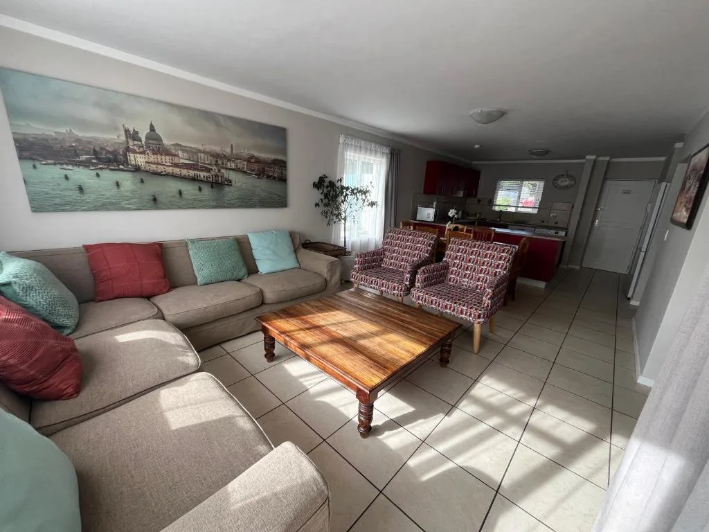 Spacious lounge with beige sofa, patterned armchairs, wooden coffee table