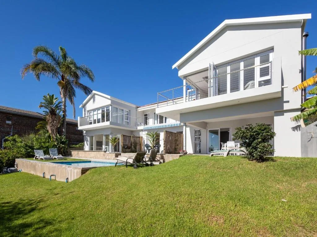Modern white two-story home with pool, palm trees, and manicured lawn