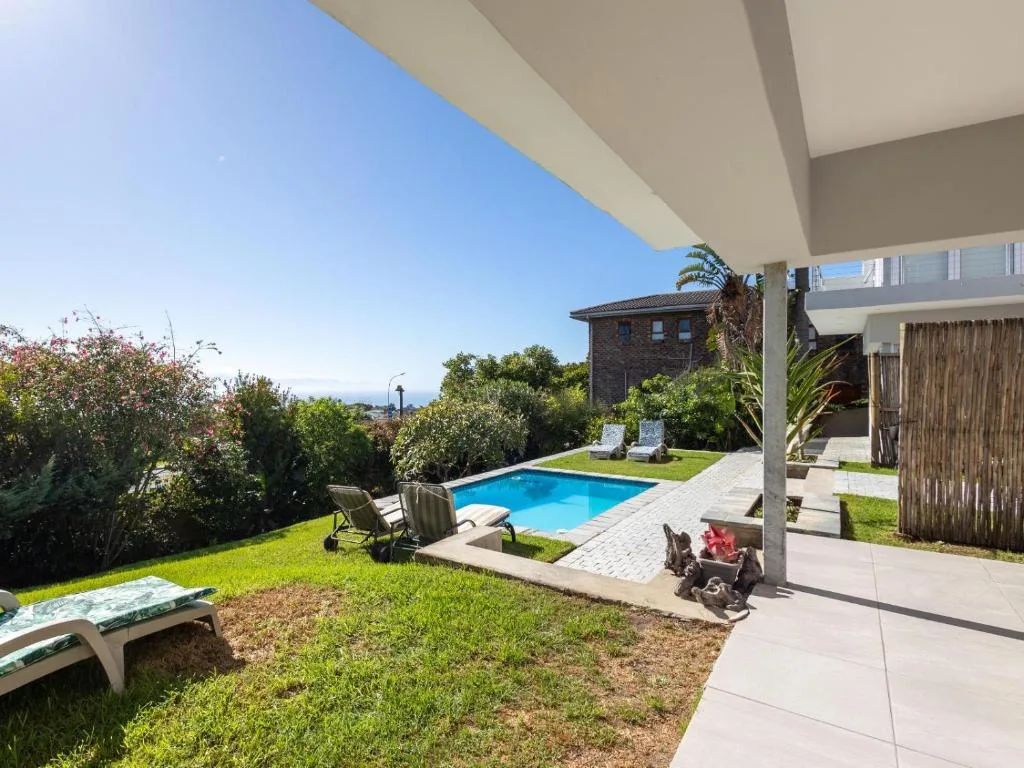 Sparkling blue swimming pool surrounded by manicured lawn and garden landscaping