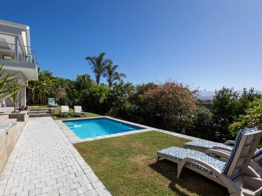 Swimming pool with loungers and mountain views on sunny day