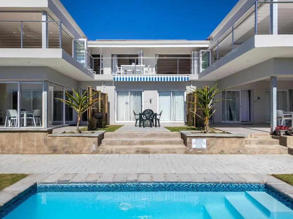 Sparkling swimming pool with modern apartment building and deck beyond