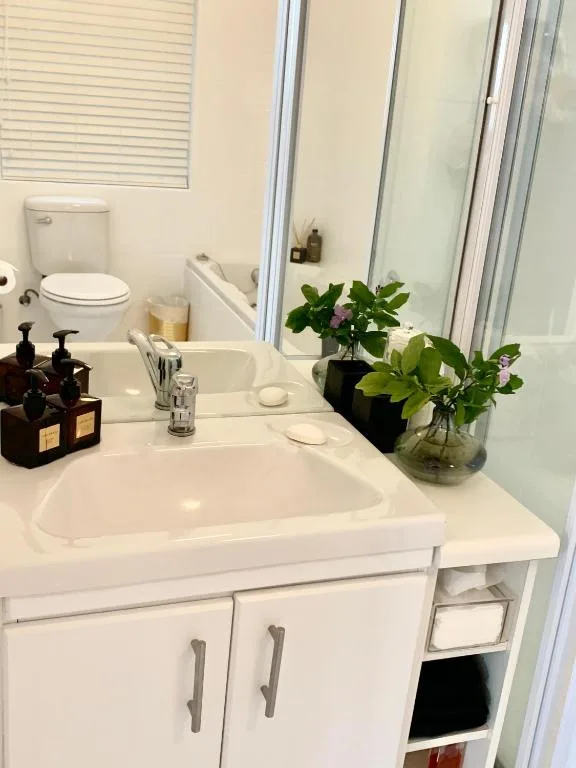 Clean white bathroom vanity with fresh flowers and toiletries displayed