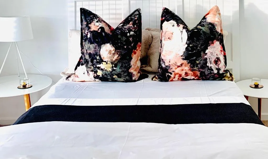 Modern bedroom with artistic floral pillows and crisp white bedding