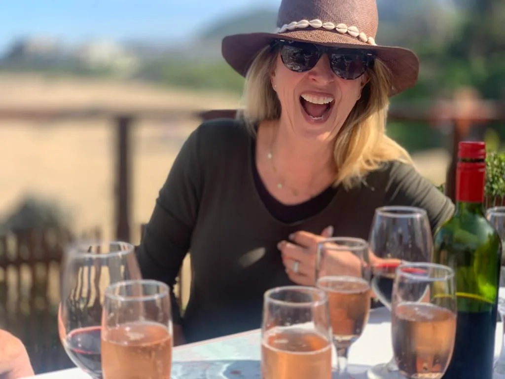 Woman enjoying wine and outdoor dining with scenic landscape views