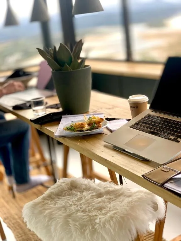 Workspace with laptop, succulent plant, coffee cup, and pastry plate