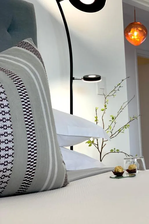Bedroom detail with decorative pillows, pendant light, and minimalist bedside styling
