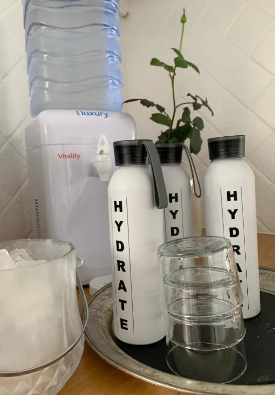 Water dispenser with hydrate bottles and glass storage on counter
