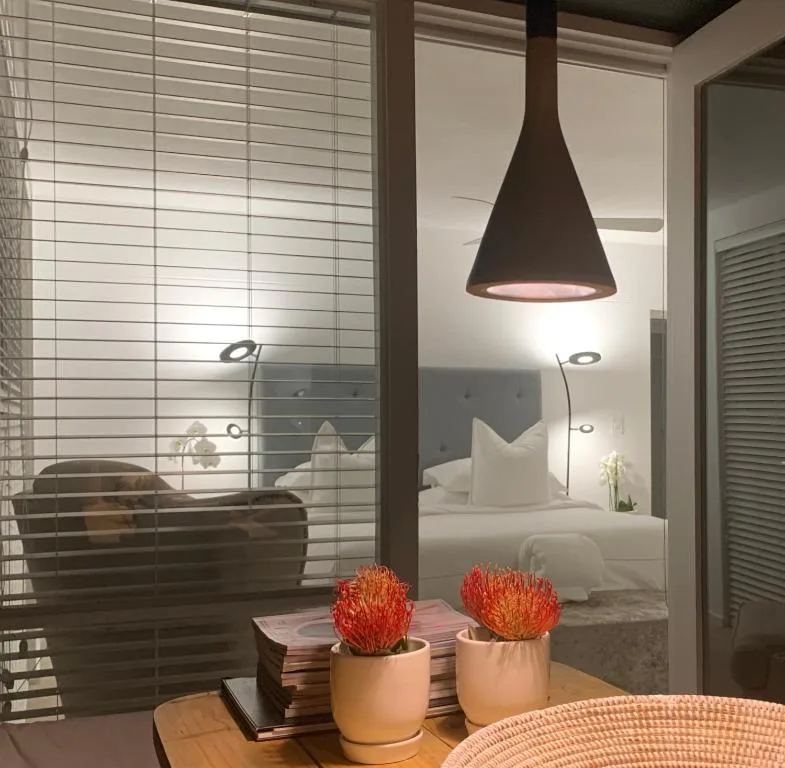 Modern pendant lamp above potted protea flowers and bedside decor