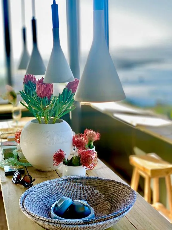 Elegant table setting with potted proteas, blue bowl, ocean view backdrop