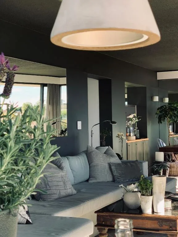 Modern lounge with gray seating, pendant lighting, and garden views