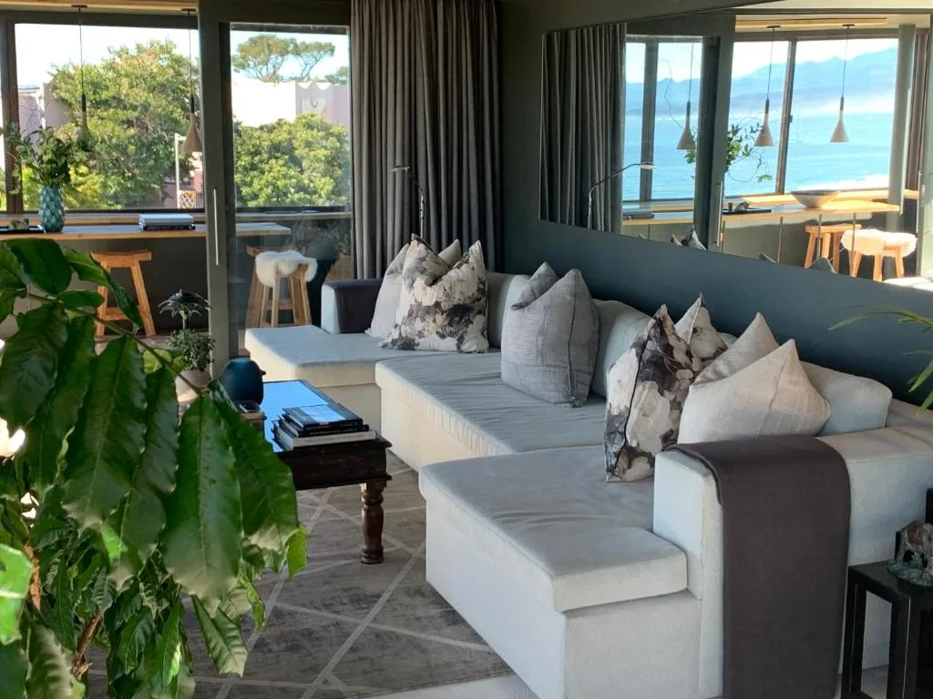 Modern lounge with ocean views through expansive windows and coastal mountains