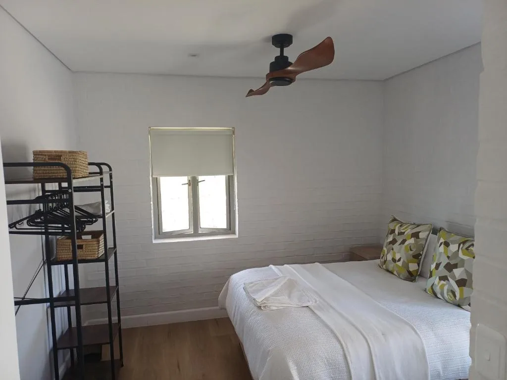 Bright bedroom with single bed, bunk beds, and ceiling fan