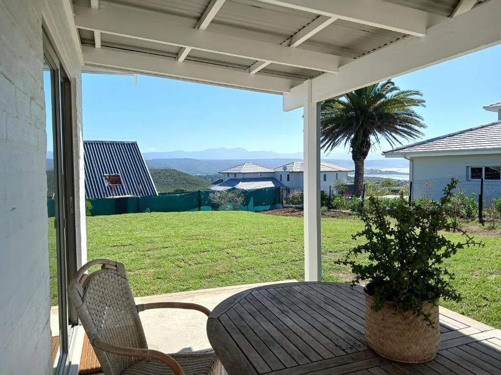 Covered patio with seating overlooking manicured lawn and mountain views