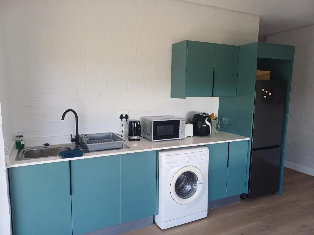 Turquoise kitchen with sink, microwave, washing machine, and black fridge